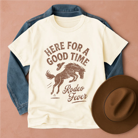 T-shirt with 'Here for a Good Time Rodeo Fever' design, blue jacket, and brown hat on a beige background