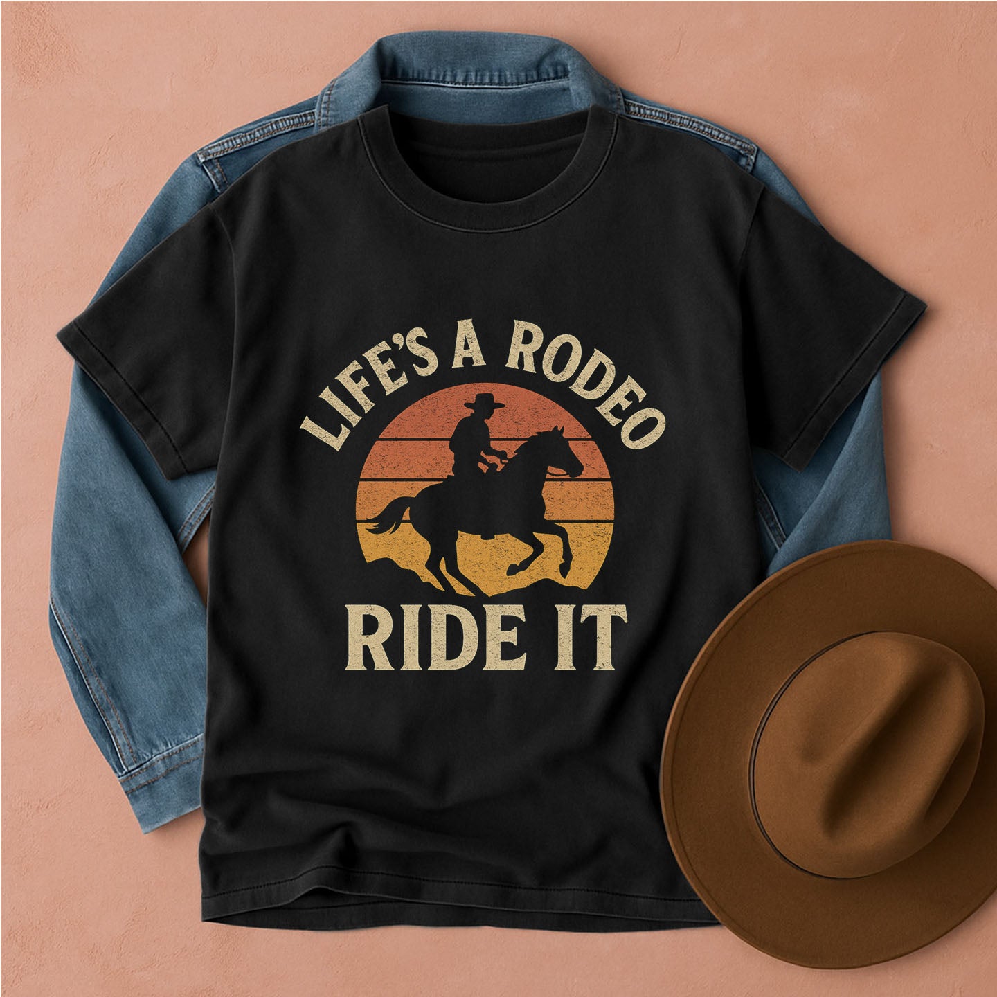 Black t-shirt with 'Life's a Rodeo, Ride It' graphic on a beige background