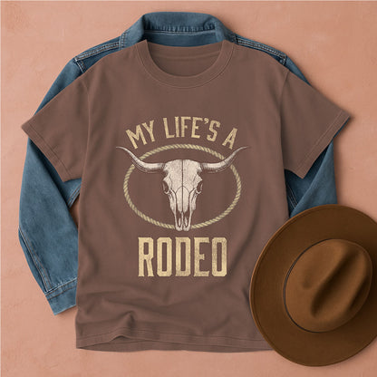 Brown t-shirt with 'My Life's a Rodeo' graphic and blue denim jacket, brown hat on beige background