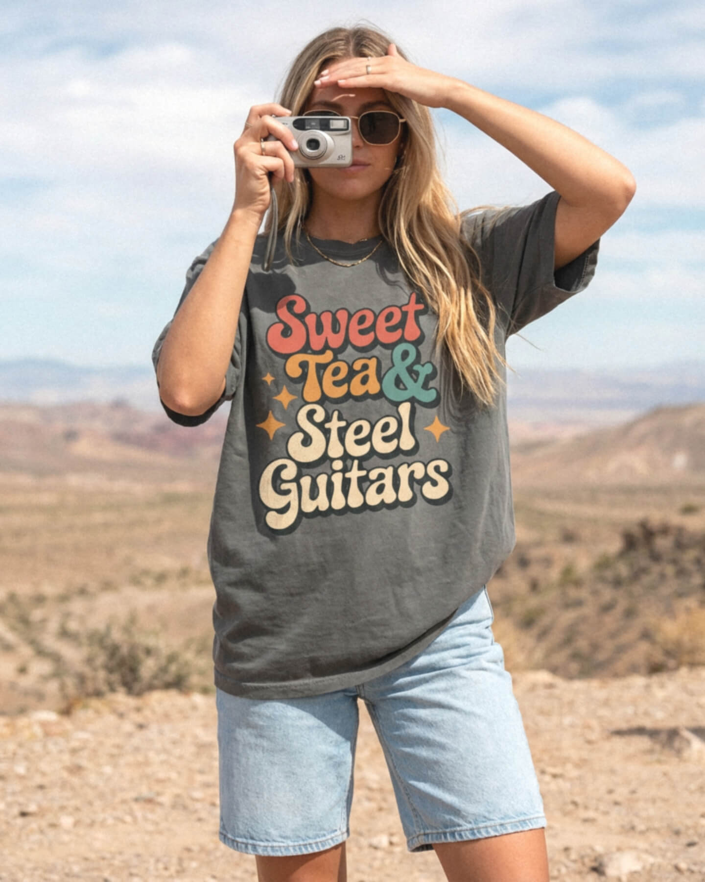 Person wearing a 'Sweet Tea & Steel Guitars' Comfort colors 1717 Pepper t-shirt in a desert setting