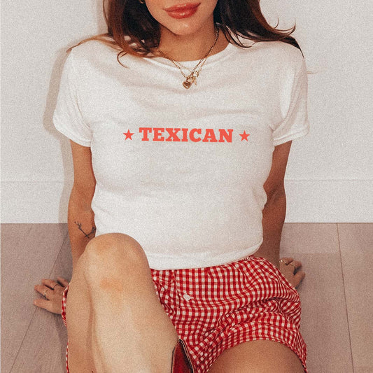 Person wearing a white t-shirt with 'TEXICAN' printed in red, sitting on a light-colored floor.